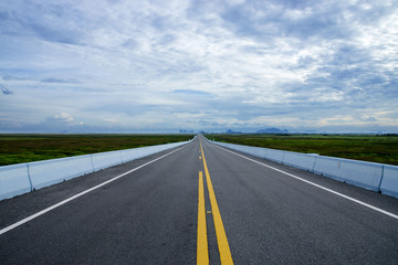 Fototapeta premium Empty road and the yellow traffic lines with clouds.