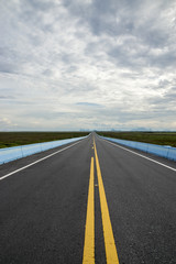 Fototapeta premium Empty road and the yellow traffic lines with clouds.