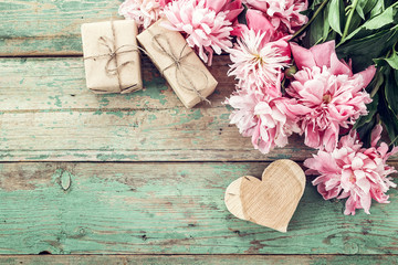 Background with pink peonies, gift box and a wooden heart on old
