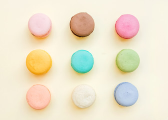 Sweet colorful French macaroon biscuits on pastel yellow background