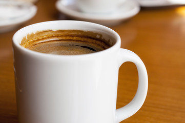 Close-up white Cup of coffee on the wooden table at a small cafe