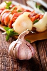 Garlic bud on old wooden board in front of skewers