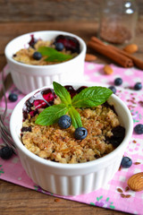Berry crumble with oatmeal and almonds on wooden background