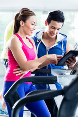Fototapeta premium Coach evaluating performance of woman on treadmill
