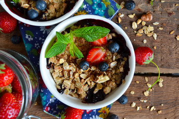 Berry crumble with oatmeal and almonds on wooden background