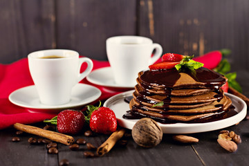 .chocolate pancakes with chocolate sauce and strawberries. coffee. breakfast