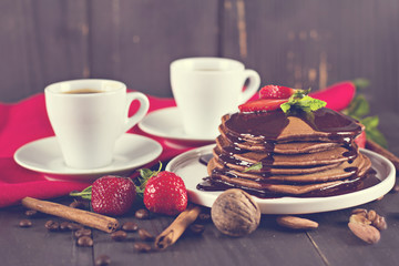 .chocolate pancakes with chocolate sauce and strawberries. coffee. breakfast