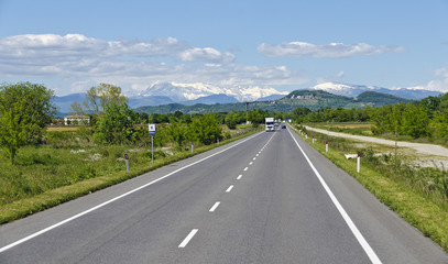 Gerade Autostraße mit verschneiten Bergen im Hintergrund