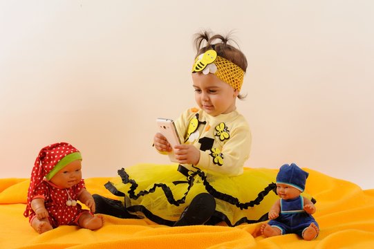 Cute and happy baby with doll and phone, smiling, laughing