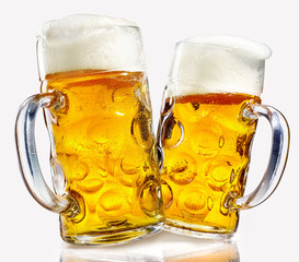 Two glass beer mugs full of golden lager