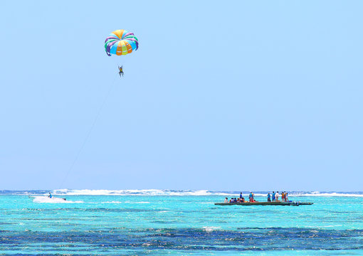 Parasailing over Indian Ocean near Mauritius Island. Summer on the beach. Outdoor sports and activities.