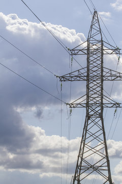 Electric power transmission lines and electricity pylon against blue sky. Low angle view