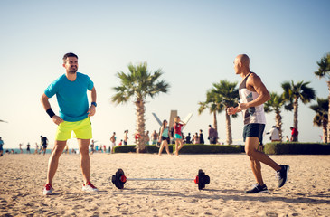 Two handsome athletes working out at beach.
