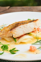 Pike perch fillet with leeks and beurre Blanc served in a white plate closeup