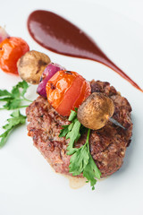 Steak and vegetables on skewers, served on a white plate