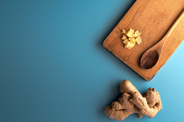 Raw ginger root with wooden kitchenware in blue background. Herb ingredient from china