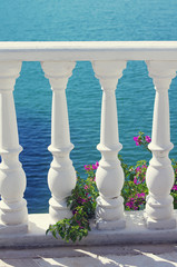 Balustrade and pink flowers of Bougainvillea against the blue sea. A summer background with the sea