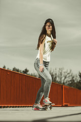Teen girl skater riding skateboard on street.
