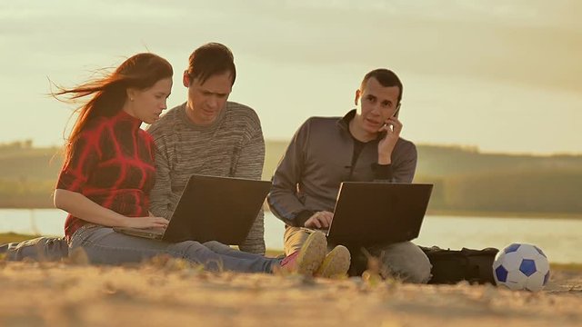 on the sand working with laptop the three people Slow motion video