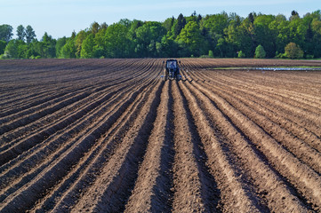 Tractor with a seed drill on a plowed field.