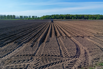 Tractor with a seed drill on a plowed field.