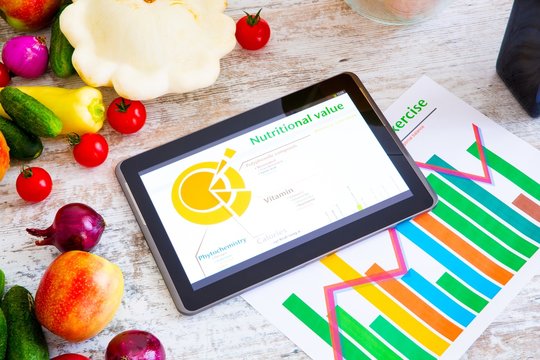 Organic food and a Tablet PC showing information about healthy nutrition and phytochemical composition..
