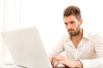 Attractive young man sitting at the table with a laptop computer..