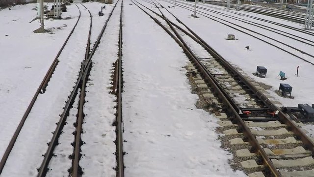 Low altitude motion aerial shot of several railway tracks and switches in snow