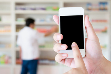 women using smart phone in pharmacy blurred background