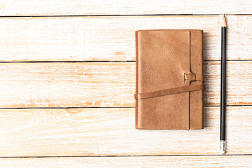 Fototapeta premium Leather diary notebook with pencil on white wooden background, B