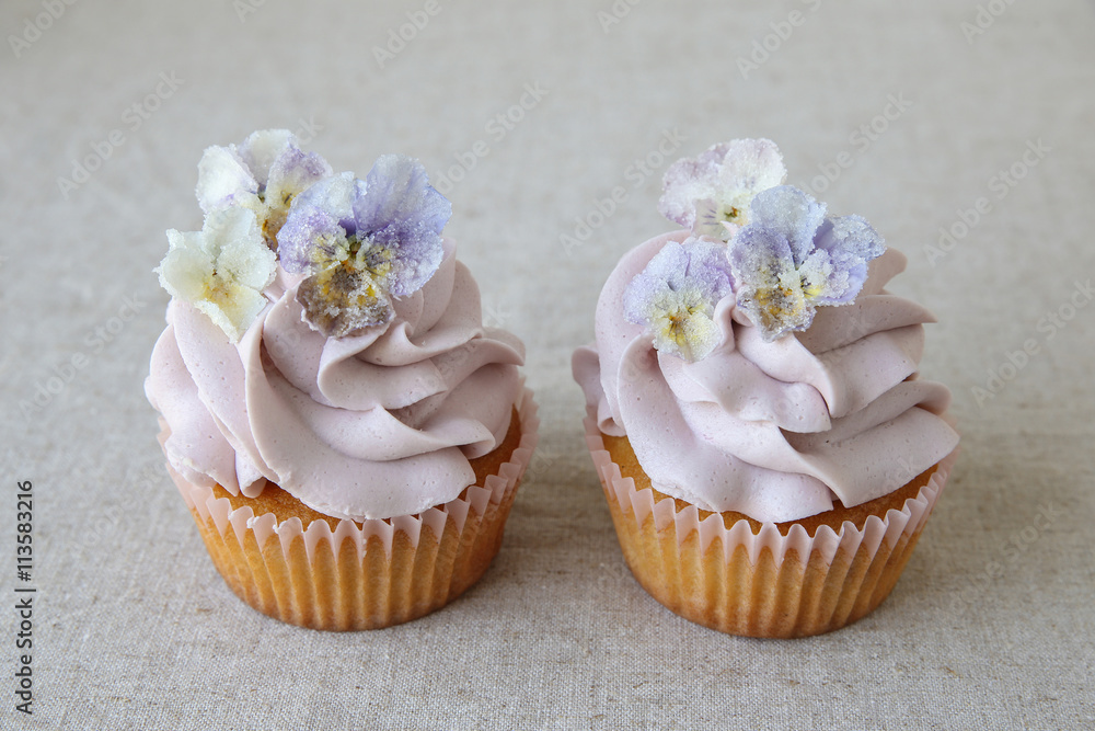 Wall mural purple cupcakes with sugared edible flowers on linen background.