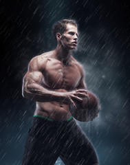 Shirtless basketball player under rain drops.