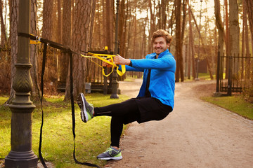 Sporty male exercising with fitness trx.