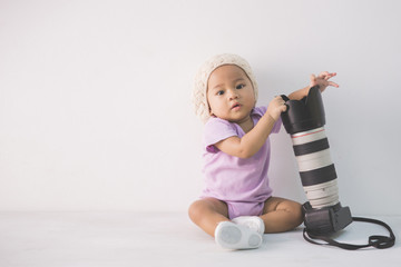 Naklejka premium little baby girl sitting on the floor holding dslr camera
