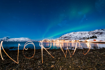 Norway written by flashlight, northern lights on background in the sky