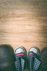 Daddy's boots and baby's sneakers, on wood background, fathers d