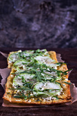 pie with zucchini, green peas, cheese and arugula on the old wooden background. vegetarian puff pie.