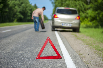 Male driver with spare wheel after breakdown