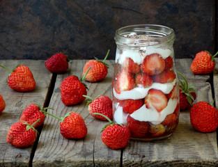strawberries and cream in a jar on a wooden background