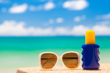 Sunscreen and sunglasses on tropical beach