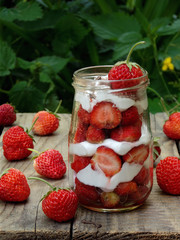 strawberries and cream in a jar on a wooden background