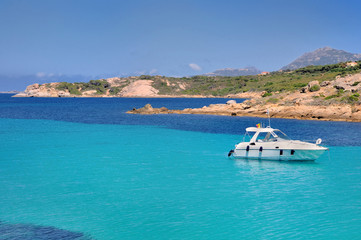 Fototapeta na wymiar bateau sur mer turquoise près des côtes rocailleuse - Corse