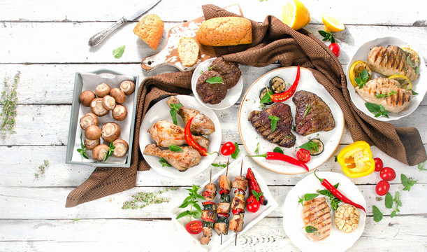 Assorted grilled meats and vegetables on  wooden background.
