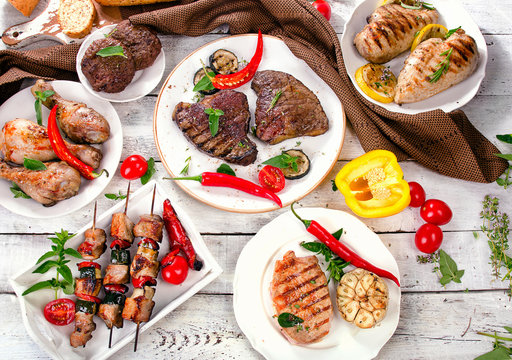 Assorted grilled meats and vegetables on a wooden background.