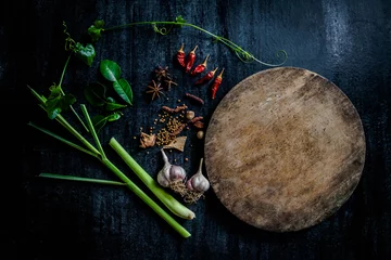 Photo sur Plexiglas Herbes Herbs and spices around empty cutting board on dark stone backgr