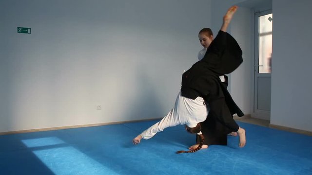 Two girls in black hakama practice Aikido on martial arts training