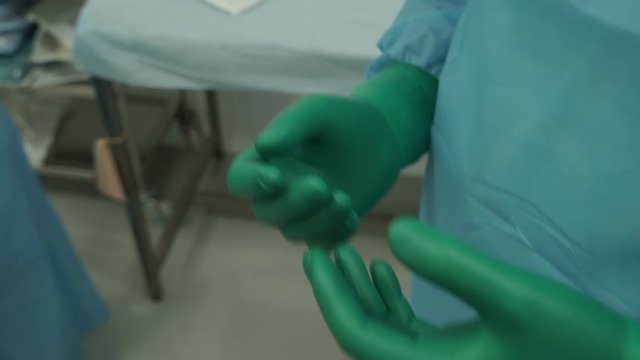 A surgeon preparing for surgery puts on gloves