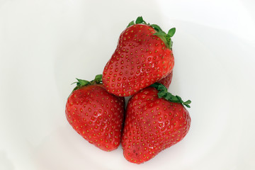 Strawberry. Ripe strawberries. Red delicious strawberries on white plate on wooden table. Close up of fresh strawberries on white background. Organic healthy food.