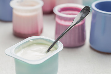 Yogurts assortment  in plastic bowls on light cloth background. Natural and fruit healthy, diet, gourmet dessert for granola breakfast. Sweet yoghurts closeup.