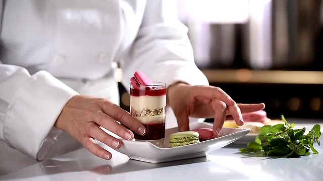 closeup on hands of a pastry chef depositing a mint leaf 